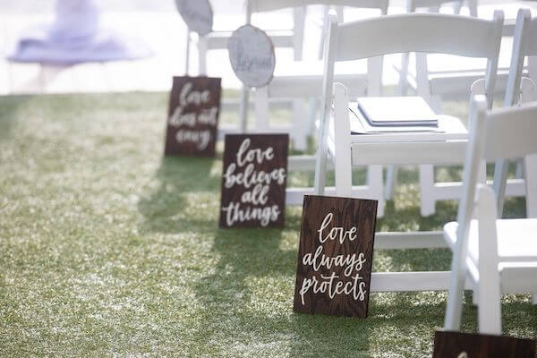 wooden LOVE IS signs with quotes from 1 Corinthians lining the aisle at a clearwater Beach wedding ceremony