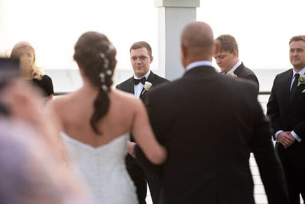 Groom watching as his bride-to-be walks down the aisle during their Clearwater Beach wedding