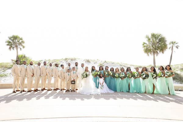 large wedding party with groomsmen in tan suits and bridesmaids in ombre tones of ocean blue colors 