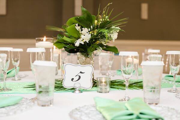 wedding reception table with lush tropical bridal party bouquets repurposed as centerpieces