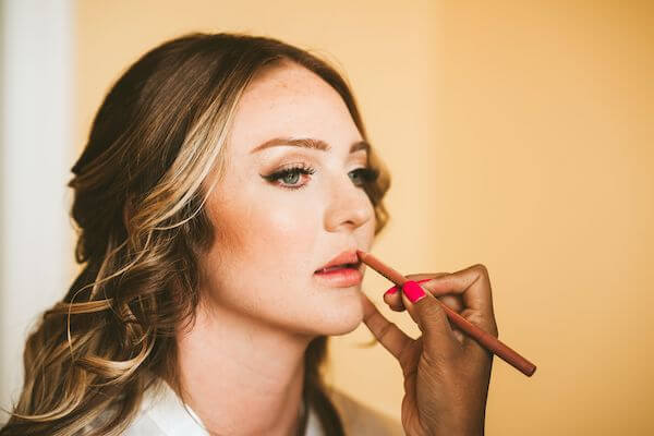 makeup artist applying lipstick to bride before her Clearwater Beach wedding