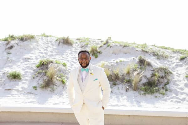 Groom in a classic white tuxedo with sea foam tie and pocket square before his Hyatt Regency Clearwater Beach wedding