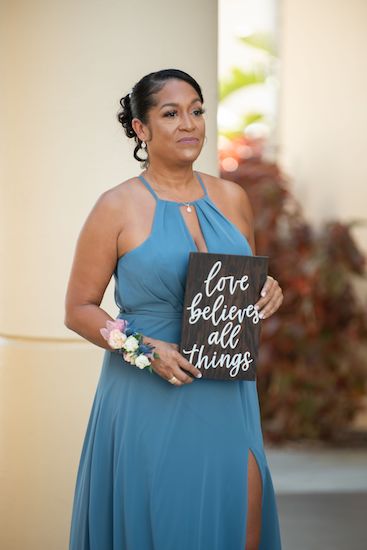 wedding attendant carrying a plaque with part of the 1 Corinthians Love Is scripture