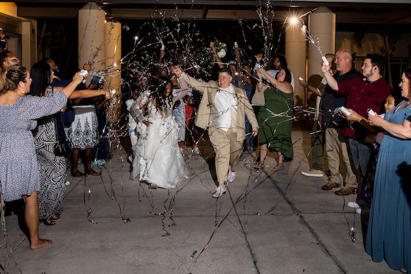 two brides exiting their wedding in a shower of river confetti