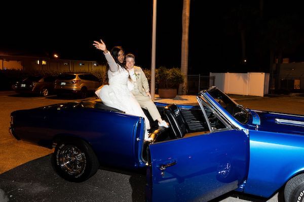 two brides making their gran exit in a classic convertible