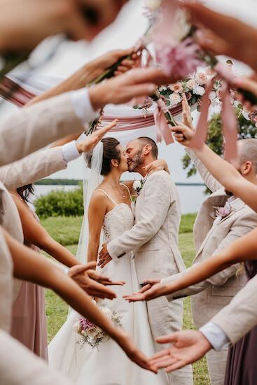 bride and groom kissing surrounded by their wedding party