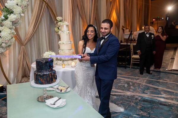 groom cutting his Star Wars themed grooms cake with a lightsaber