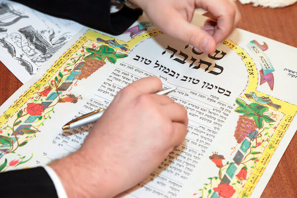 Man signing a ketubah at a traditional Jewish wedding