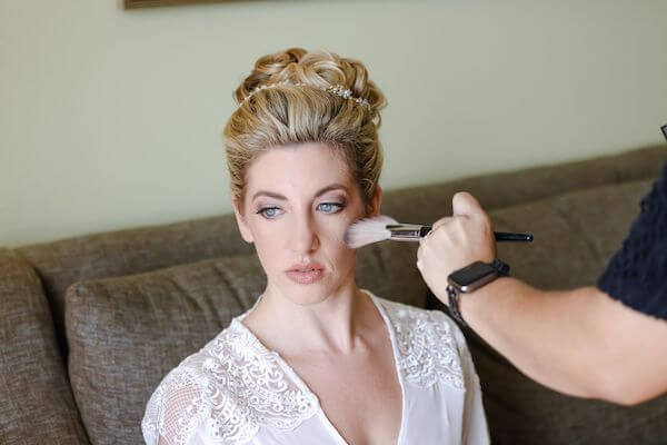 touching up a brides makeup on her wedding day