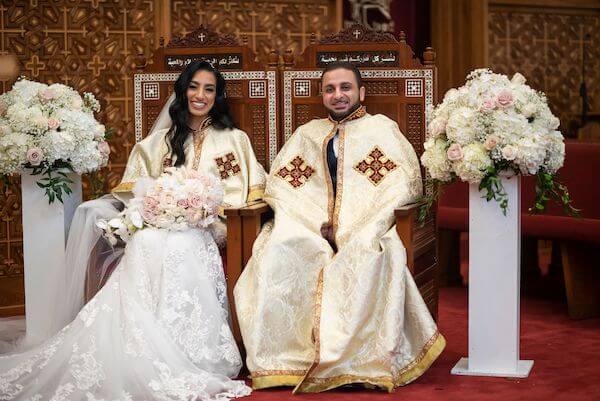 Bride and groom wearing white and gold robes during their Tampa bay Coptic Orthodox wedding ceremony