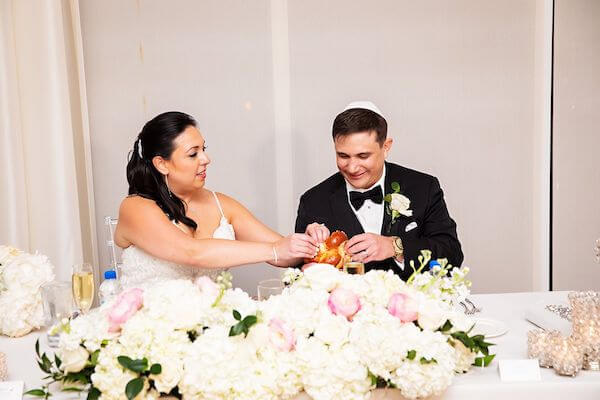 Jewish bride and groom breaking challah