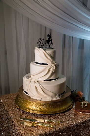 three tiered white wedding cake with sugar fabric drape