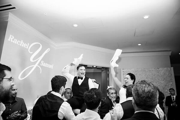 Bride and groom in chairs during a hora 