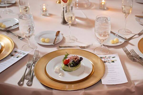 wedding place setting with a gold charger plate, preset salad and custom menu card