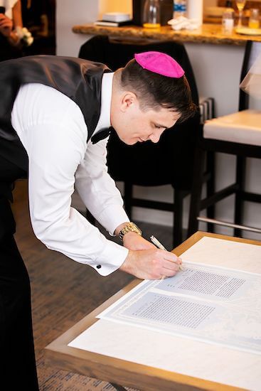 Groom signing the ketubah during his Jewish wedding ceremony