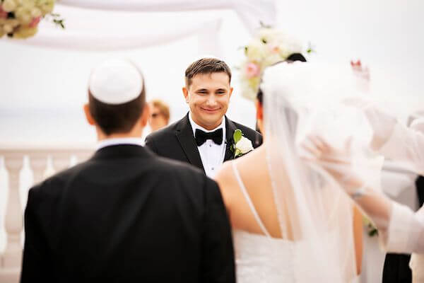 Groom looking on as his bride to be walks down the aisle with her parents