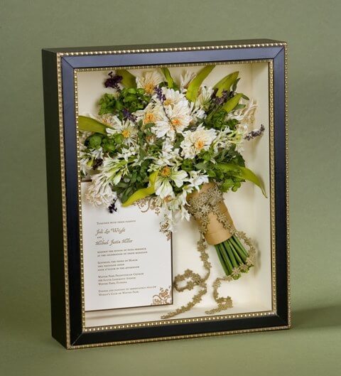 dried flowers are rearranged to recrete a bridal bouquet displayed with the couple's wedding invitation