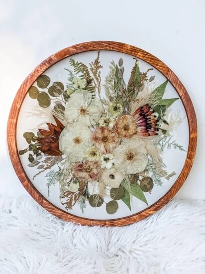 dried and pressed bridal bouquet displayed in a round wooden frame under glass