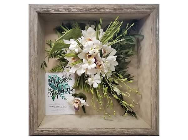 dried bridal bouquet, boutonniere and invitation inside of a shadowbox