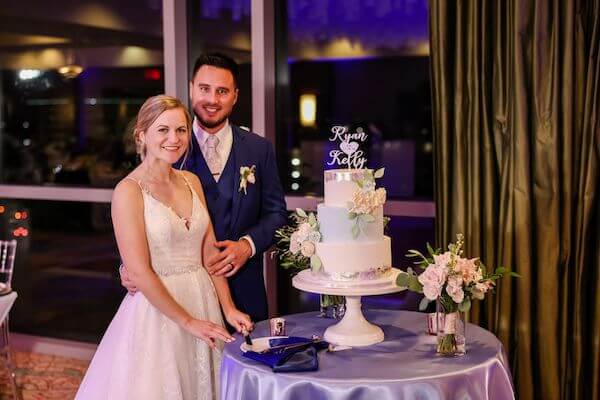 Bride and groom posing for photos beofre cutting their wedding cake by Hands on Sweets of Tampa