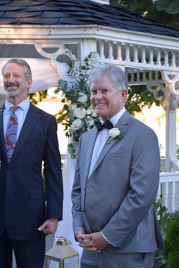 groom smiling as his bride walks down the aisle