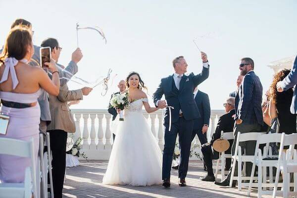 Happy bride and groom leaving their Clearwater Beach wedding with ribbon wands