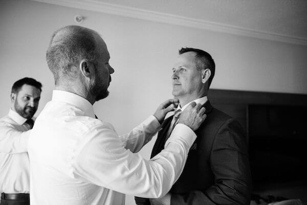 groomsman fixing the grooms tie