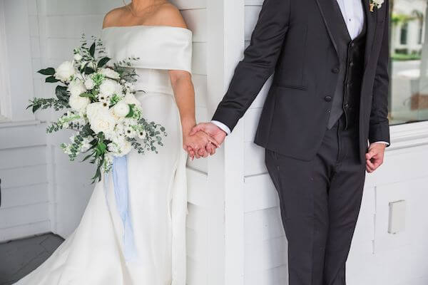 bride and groom touching hands but not seeing each other