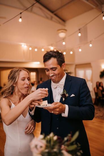 Bride and groom smashing wedding cake in each others faces