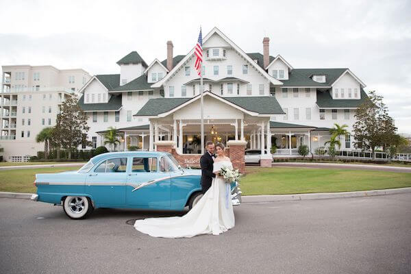 bride and groom posing with a vintage car at the Belleview Inn