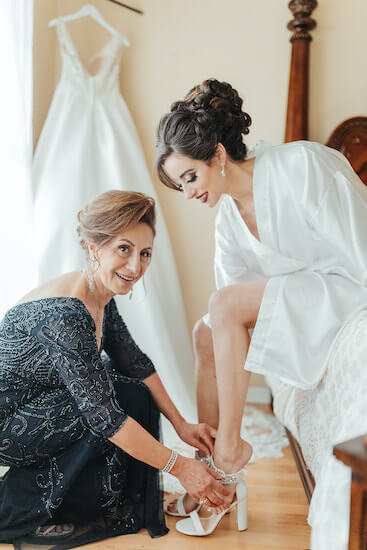 Mother of the bride helping daughter put on her shoes