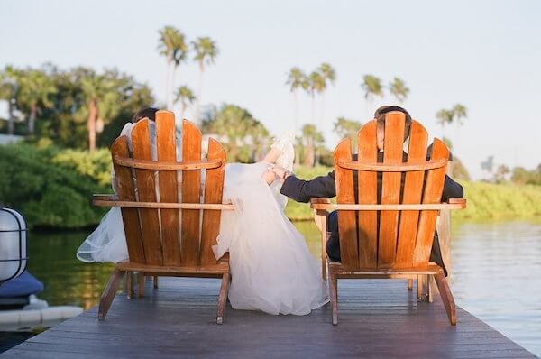 bride and groom in beach chais sitting on a dock