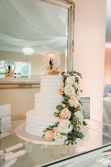 Three tiered white wedding cake with fresh flowers