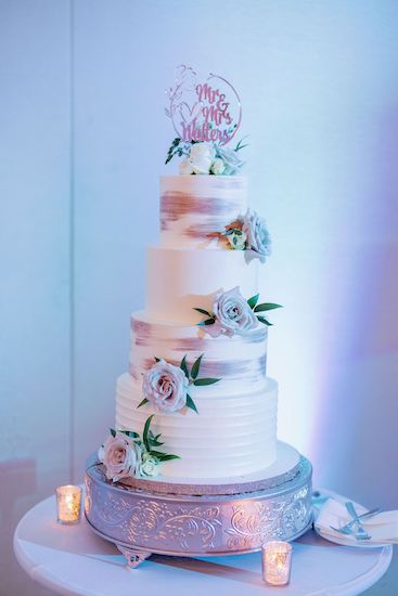 four tiered wedding cake with greenery