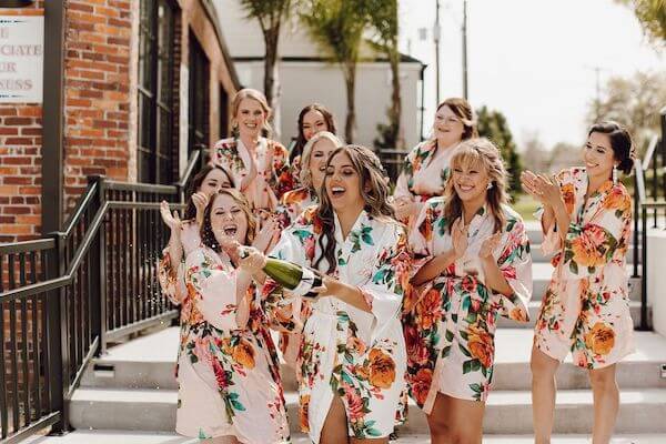 Bride popping some champagne with her wedding party