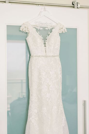 wedding gown hanging against a sea glass wall