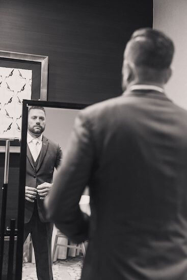 groom looking in the mirror while getting dressed