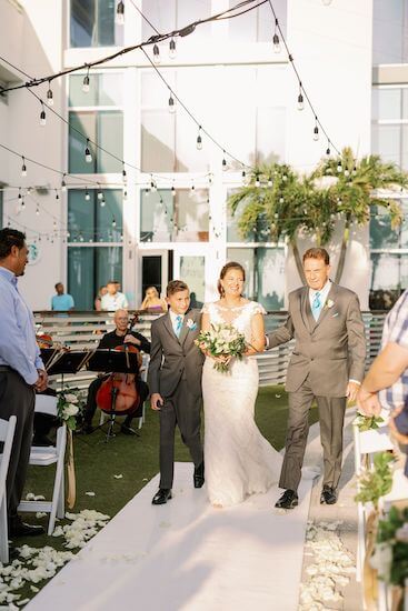 Bride being escorted down the aisle by her father and son