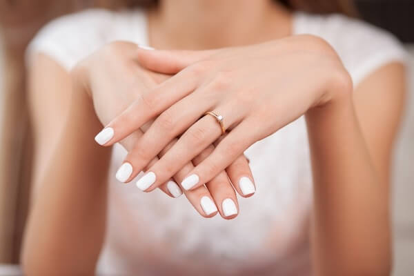 Close up of hands of woman showing the ring with diamond. She is engaged