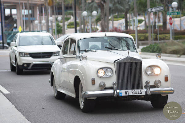 Bride and groom heading to their wedding reception in a white Rolls Royce