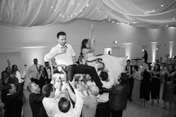 Bride and groom lifted on chairs during a traditional hora