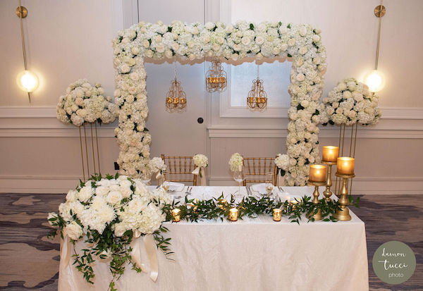 Sweetheart table with lush white floral frame and candles