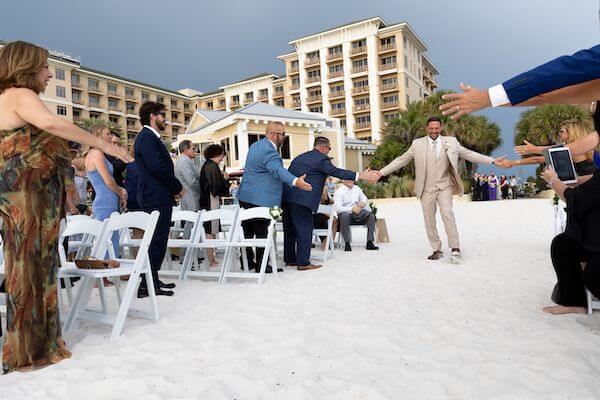 Groom giving high fives as he walks down the aisle for his wedding ceremony