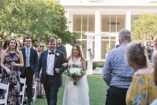 Bride holding back tears as her father walks her down the aisle