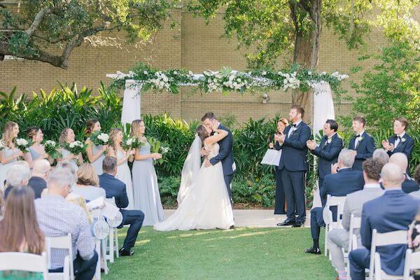 The bride and groom seal their wedding vow with a kiss in an outdoor wedding ceremony.