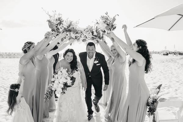 bride and groom ducking under an arch made by their wedding party