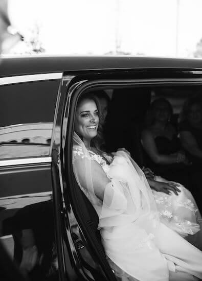 Bride coming out of a classic black limousine 