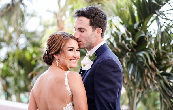 The groom kissing his bride's forehead