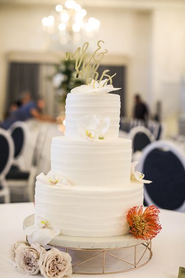 Three tiered white ruffle wedding cake with tropical flowers