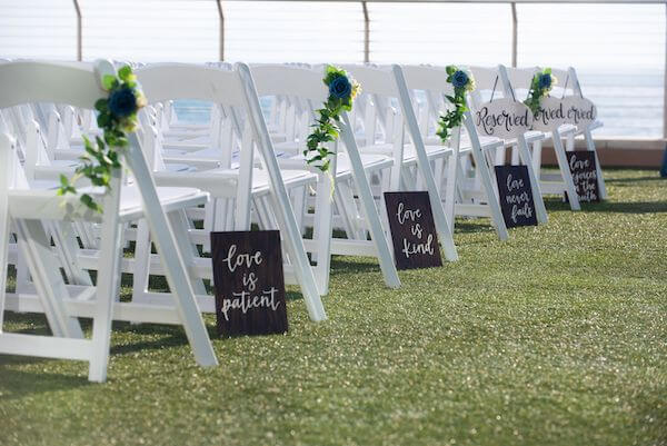 Wedding aisle with white garden chairs and bible verses from 1 Corinthians